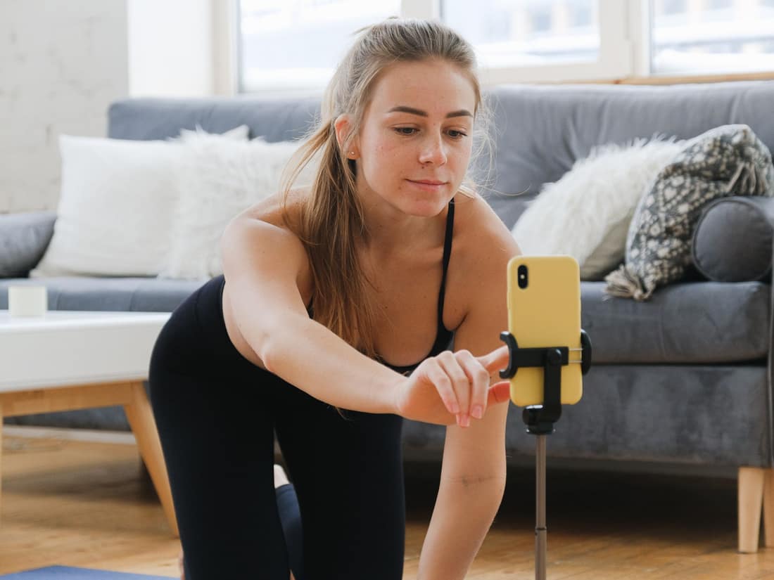 Fitness creator filming a workout with a phone on a tripod